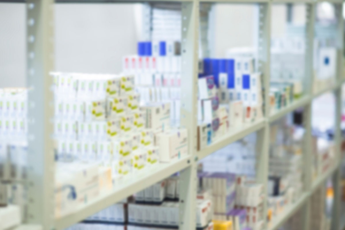 Blurred shelves of boxed medicines in a pharmacy stockroom